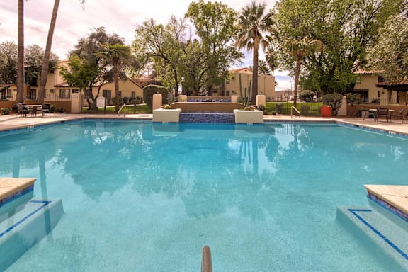 A swimming pool surrounded by palm trees and residential buildings.
