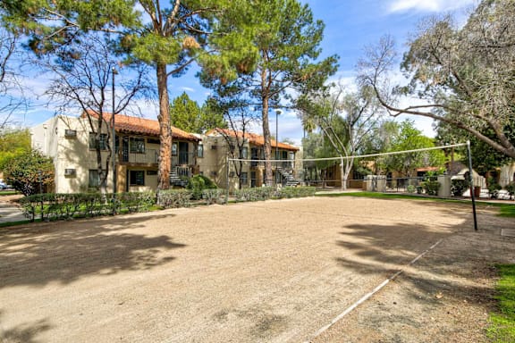 Outdoor beach volleyball court with tree-lined view.
