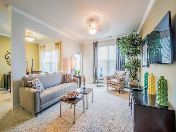 A living room with a grey couch, a coffee table, and a large mirror on the wall.