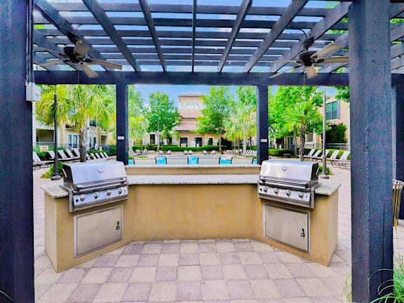 A grill is under a roof on a patio.