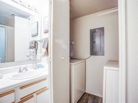 A white bathroom with a sink, mirror, and towel rack.