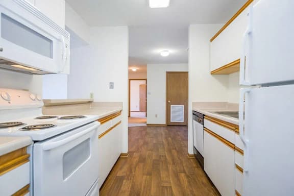 A kitchen with white appliances and wooden floors.