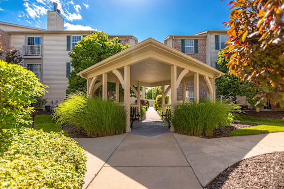 A gazebo-like structure is in the middle of a walkway with a building in the background.