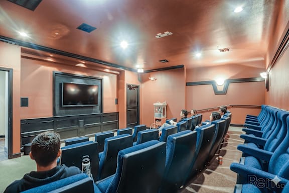 A man is sitting in a movie theater watching a movie at Remington at Memorial Apartments, Tulsa, 74133