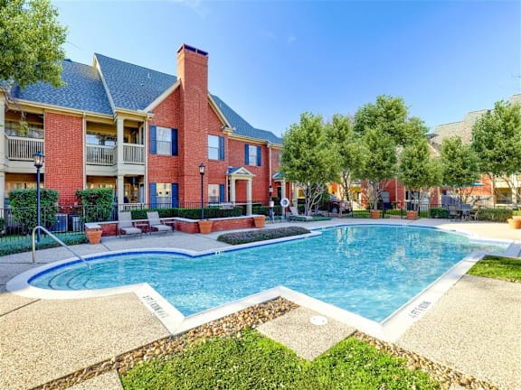 A red brick building with a pool in front.