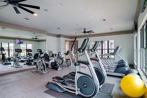 A gym with a variety of exercise equipment including treadmills, stationary bikes, and weight machines.