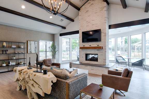 A living room with a stone fireplace and a large flat screen TV mounted on the wall.