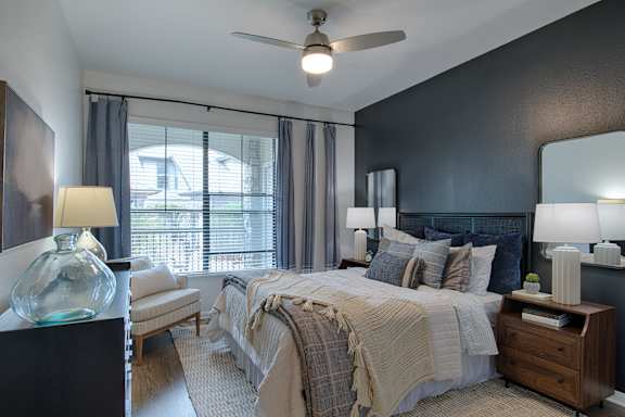 A bedroom with a bed, nightstand, and a ceiling fan.