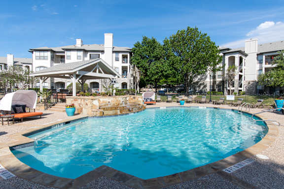 A large swimming pool in front of apartment buildings.
