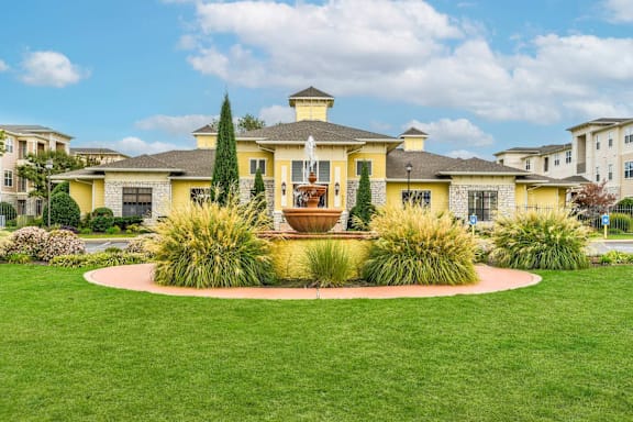 A yellow house with a fountain in front of it.