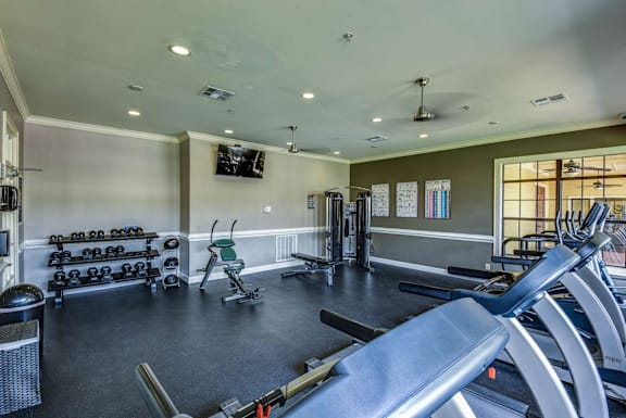 A gym with a variety of equipment including treadmills, weights, and exercise machines.
