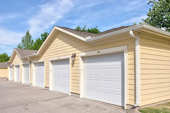 A row of garages with white doors and yellow siding.