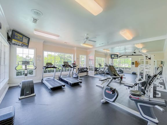 A spacious gym with treadmills, elliptical machines, and a fan.