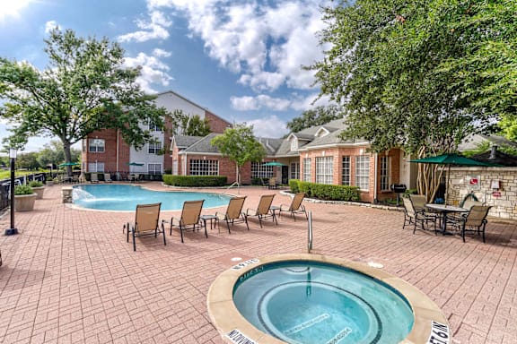 A pool surrounded by chairs and trees.