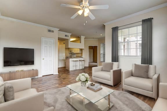 A modern living room with a glass coffee table and white furniture.