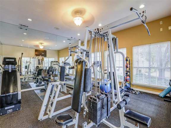 A well-equipped gym with various exercise machines and weights at Trinity Square Apartments, Dallas, TX
