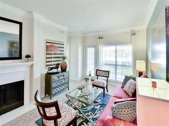 A living room with a fireplace and a glass coffee table.