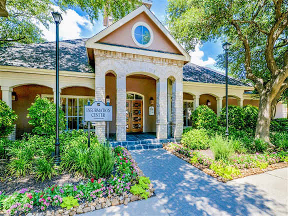 A building with a sign that says "Information Center" is surrounded by trees and plants at Bentley Place Apartments, Plano, TX 75093
