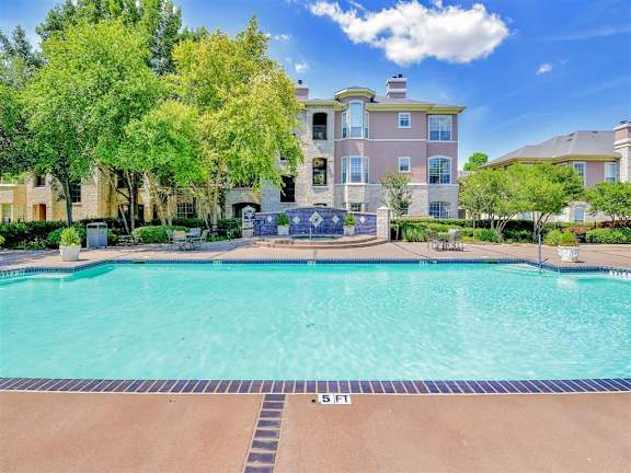 A large house with a pool in front of it at Bentley Place Apartments, Texas