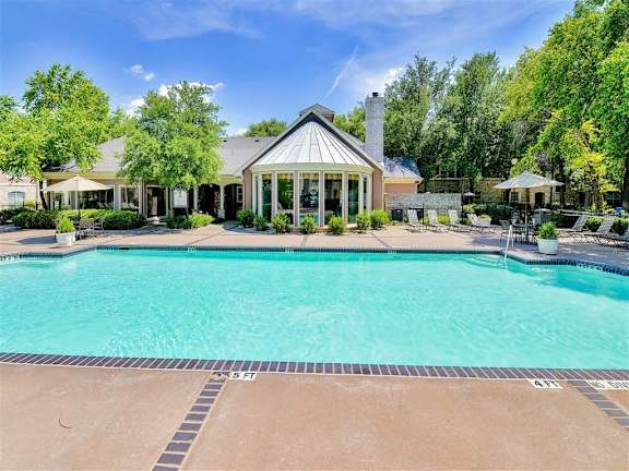 A large swimming pool in front of a house with a pool house at Bentley Place Apartments, Plano