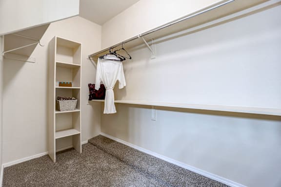 A white shirt is hanging on a clothes rack in a white room.