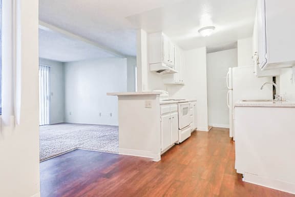 A kitchen with white cabinets and wooden floors.
