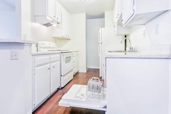 A white kitchen with a dishwasher in the middle.