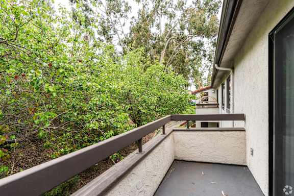 A balcony with a railing overlooks a lush green garden.