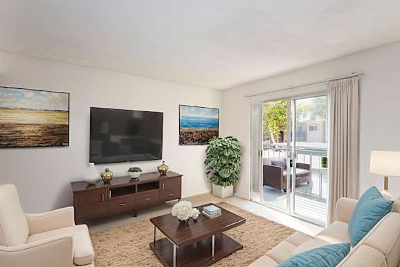 A living room with a white sofa, a wooden coffee table, and a painting on the wall  4. at Woodlake Apartments, Escondido California