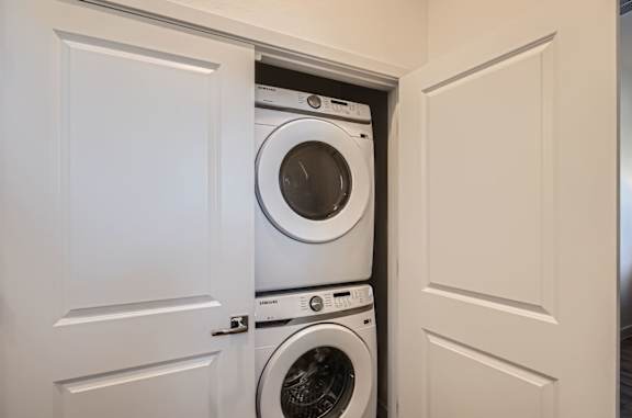 A white door is open to reveal a white washing machine inside.