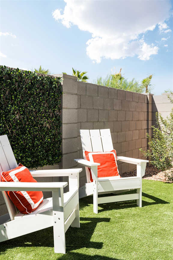 a backyard with white chairs and orange pillows a backyard with white chairs and orange pillows at Villas on Ash, Gilbert, AZ