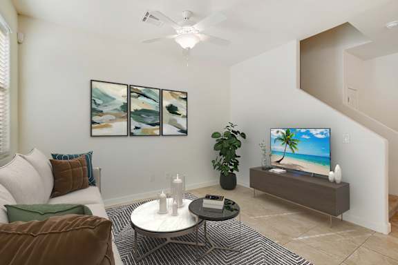 A living room with a white couch, a coffee table, a television, and a plant.
