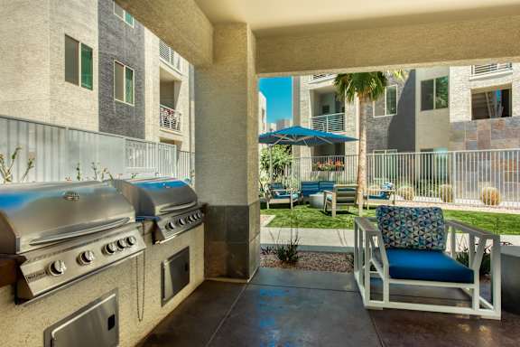 A patio with a grill and a chair with a blue cushion. at Craft at Gilbert and Baseline Apartments, Mesa, 85204