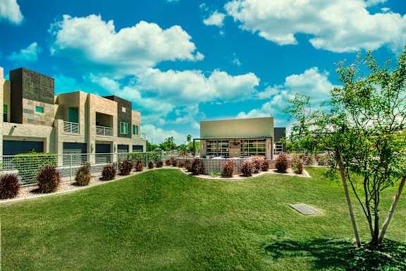 A modern building complex with a green lawn in front. at Craft at Gilbert and Baseline Apartments, Arizona