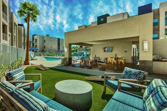 A modern outdoor seating area with a pool and palm tree. at Craft at Gilbert and Baseline Apartments, Arizona