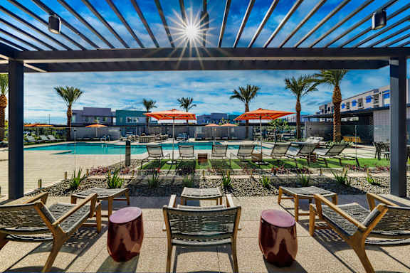 A sunny day at the pool with chairs and umbrellas.