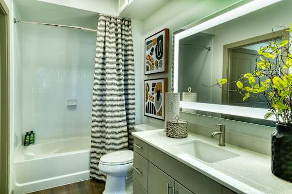 A bathroom with a white toilet, a white sink, a white bathtub, and a mirror.