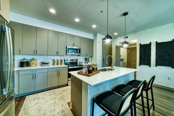 A kitchen with a white counter top and black chairs.