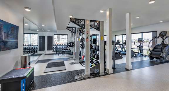 A gym with a variety of equipment including treadmills, weights, and exercise machines.