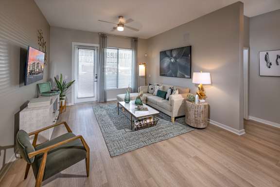 A living room with a chair, a couch, a coffee table, and a painting on the wall.