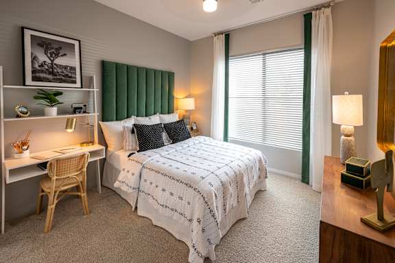A bedroom with a bed, desk, and chair.
