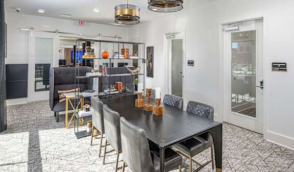 A dining room with a black table and grey chairs.