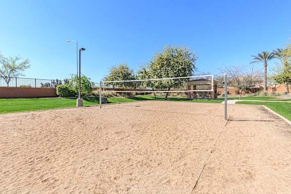 A sandy volleyball court with a net and a pole at Superstition Canyon Apartments, Apartments, Mesa, AZ