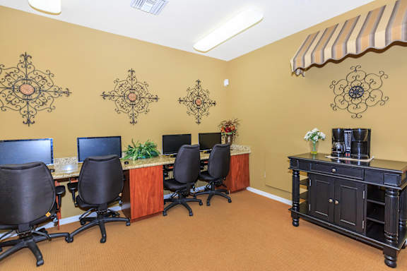A room with a brown carpet and a brown wall with a black desk and chairs. at Superstition Canyon Apartments, Mesa, Arizona
