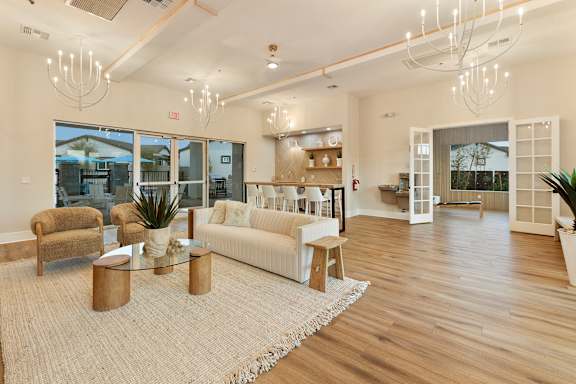 A spacious living room with a white sofa, a glass coffee table, and a rug. at Villas on Ash Apartments, Gilbert, 85234