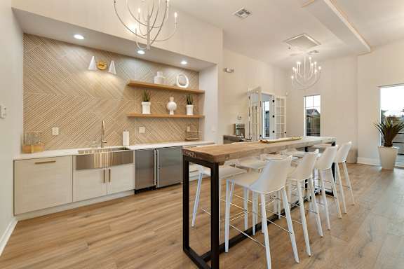 A modern kitchen with a wooden island and white chairs. at Villas on Ash Apartments, Gilbert