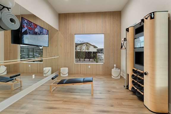 A room with a TV on the wall and a row of chairs. at Villas on Ash Apartments, Gilbert, Arizona