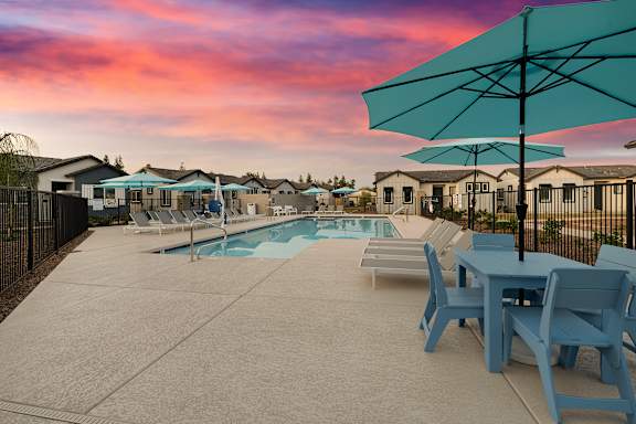 A poolside area with a table and chairs and a pool in the background at Villas on Ash Apartments, Arizona, 85234