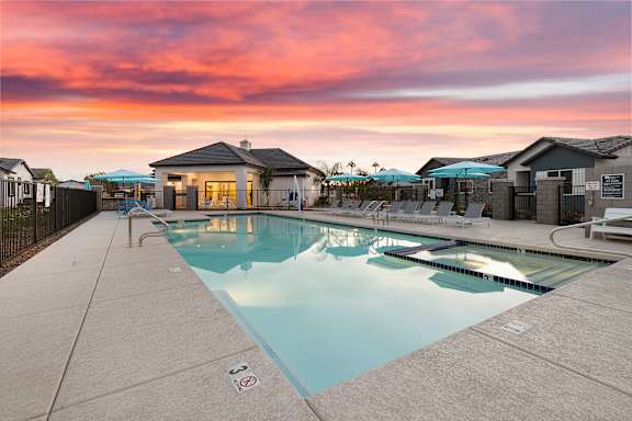 A swimming pool surrounded by a fence with a building in the background. at Villas on Ash Apartments, Apartments, Gilbert, AZ
