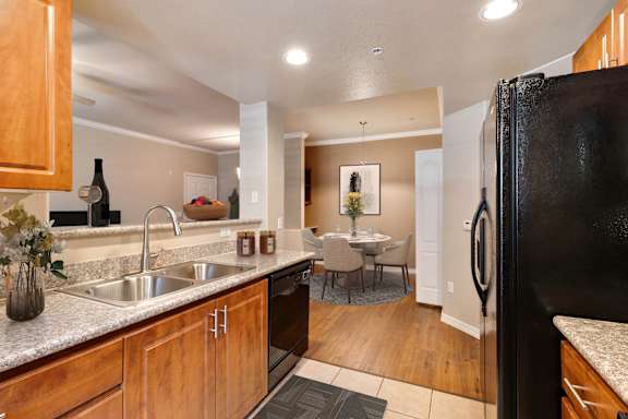 A kitchen with a black refrigerator and wooden cabinets. at Superstition Canyon Apartments, Mesa, AZ, 85209